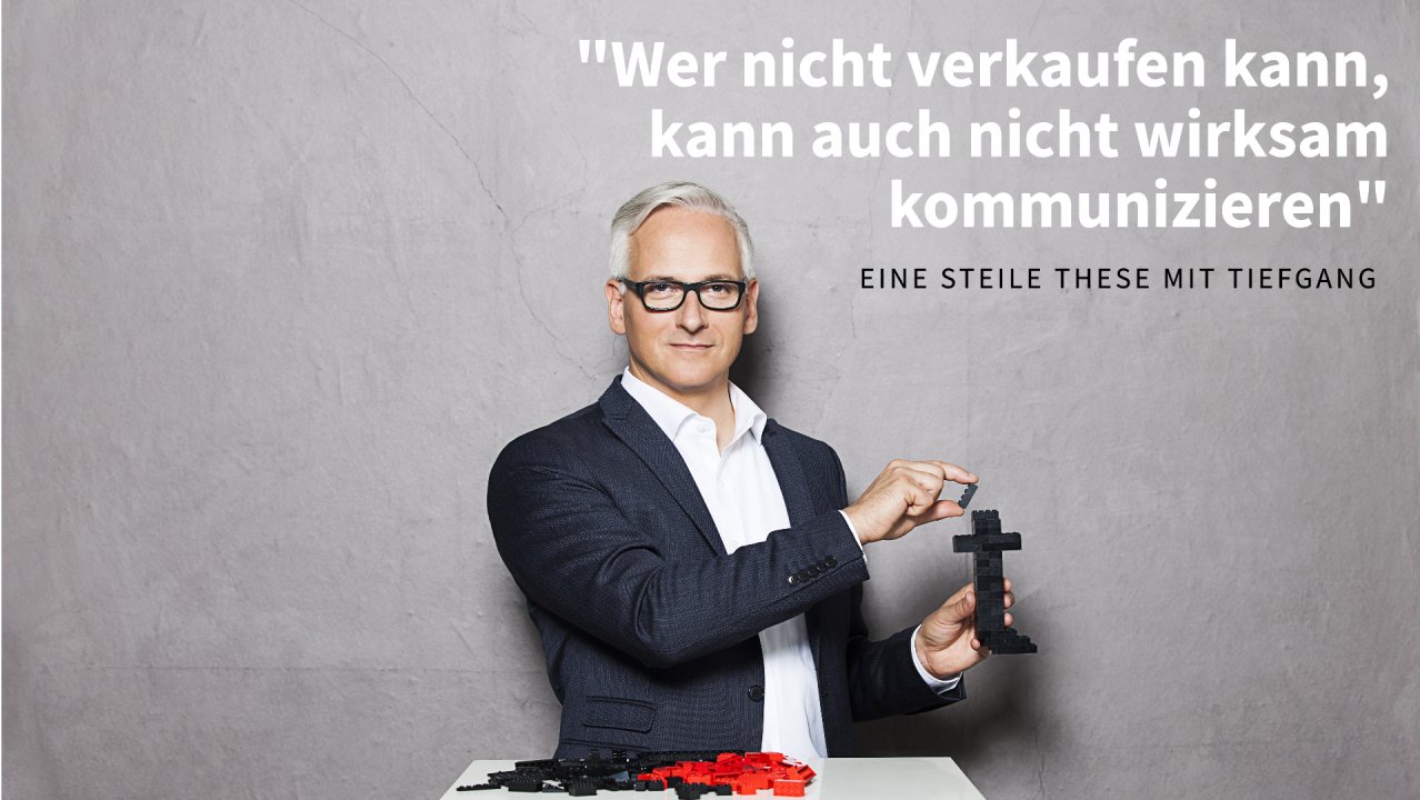 Karl Turner steckt schwarze Bausteine zu einer Figur zusammen, vor ihm liegen rote und schwarze Einzelteile
